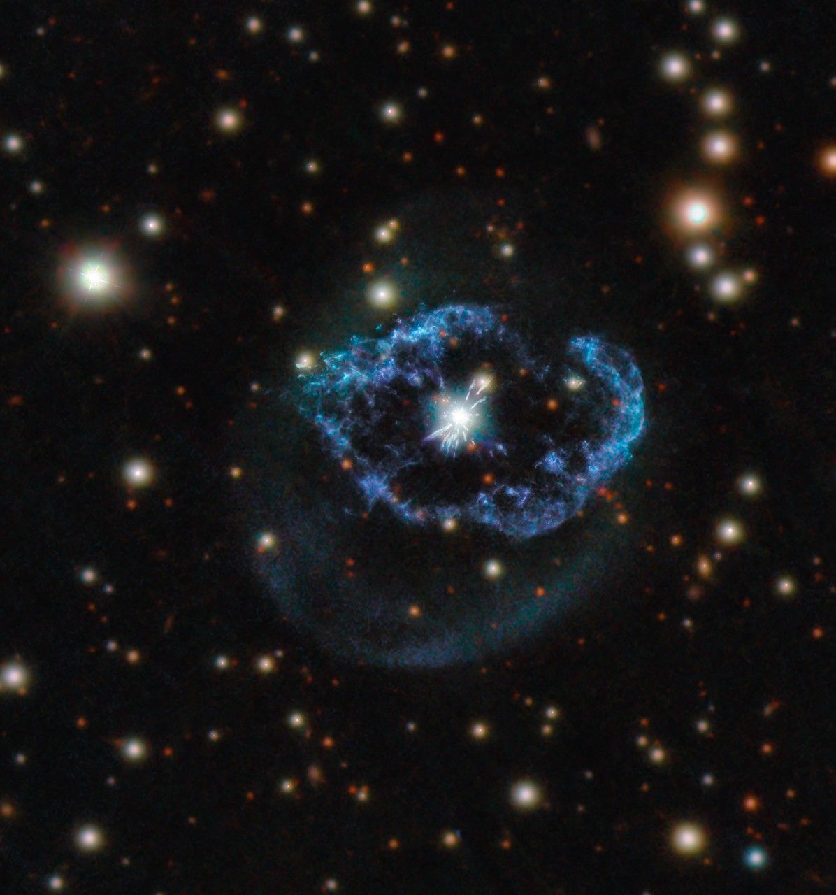 A glowing white center surrounded by a blue-purple shell/ring. Many bright stars glow in the background.